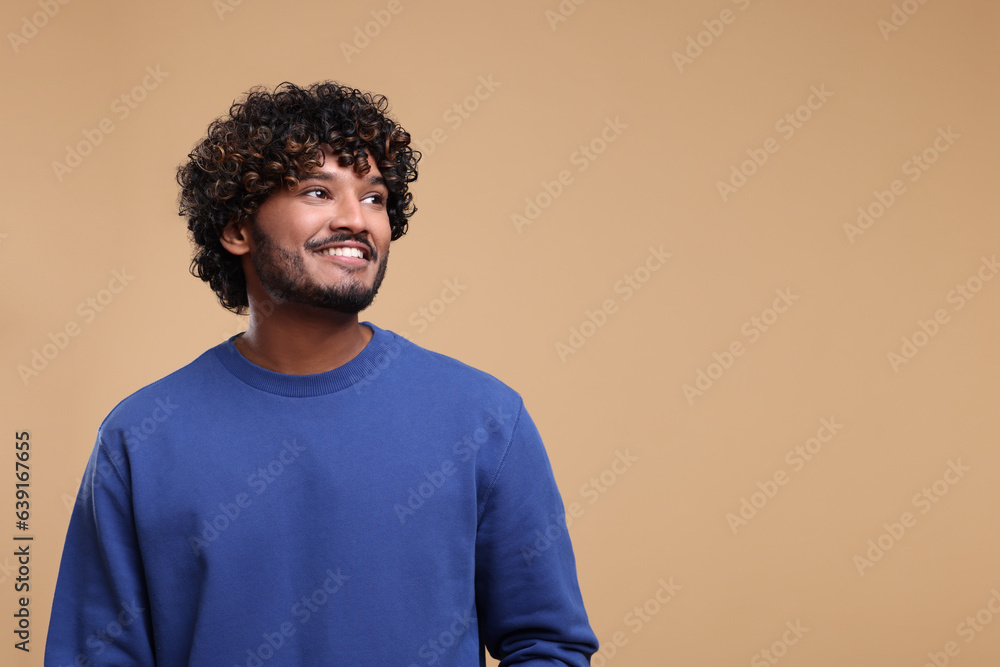 Handsome young smiling man on beige background, space for text Handsome young smiling man on beige background, space for text