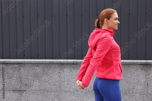 Beautiful woman in gym clothes doing exercises on street, space for text © New Africa