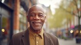 Smiling elderly African man standing in the city. A happy old African American grandfather standing outdoors on a summer day. Handsome, well dressed senior man outside, close-up portrait.