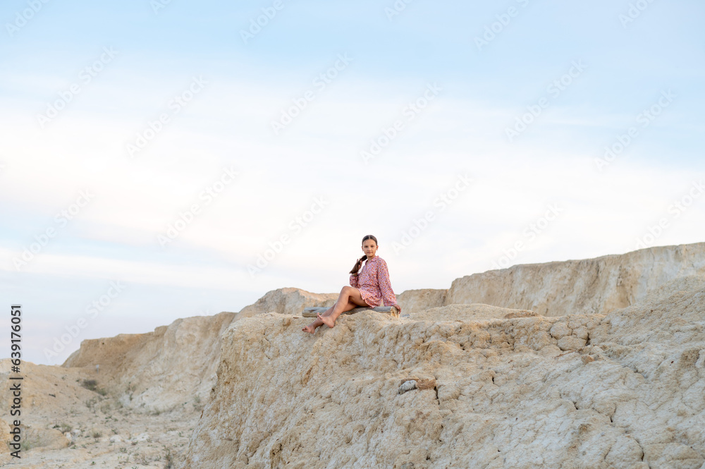 A girl sits edge of a cliff looking at the beauty of nature.
