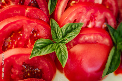 red ripe tomato and bell pepper sliced next to green basil leaves © Екатерина Абатурова
