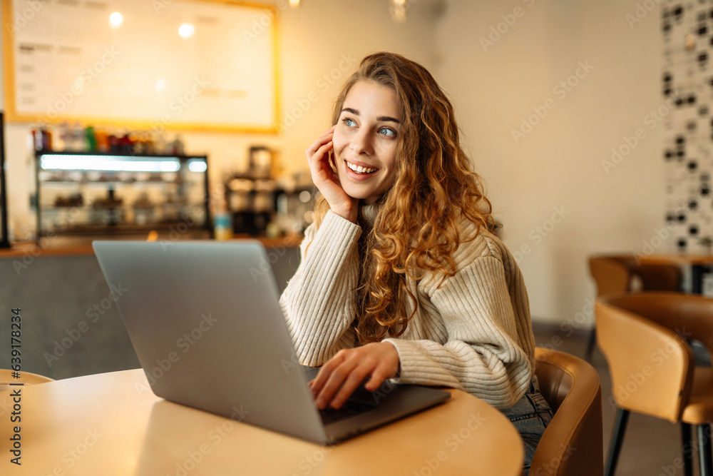 Young freelancer woman sitting in a cafe at a laptop working online. The concept of education, freelancing. Young freelancer woman sitting in a cafe at a laptop working online. The concept of education, freelancing.