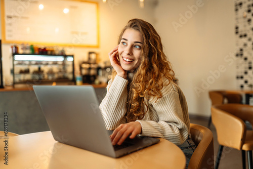 Young freelancer woman sitting in a cafe at a laptop working online. The concept of education, freelancing.