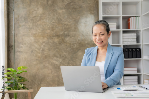 Research analytics concept, old asian businesswoman using calculator and financial document laptop to do financial mathematics on office table, tax, report, accounting, statistics