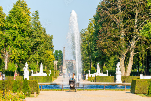 Fototapeta Naklejka Na Ścianę i Meble -  Panoramic view over garden, pools, flowers, old statues, fountains and many tourists in the city park of Potsdam, a German town of statues and sculptures, Germany, at sunny summer day