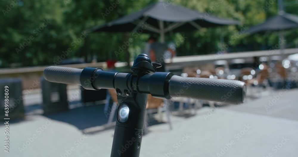 Close up on urban rental electric scooter, handlebar, kick stand and wheels. Sharing economy and concept of last kilometer. Electric scooter unlocked with smartphone app Close up on urban rental electric scooter, handlebar, kick stand and wheels. Sharing economy and concept of last kilometer. Electric scooter unlocked with smartphone app