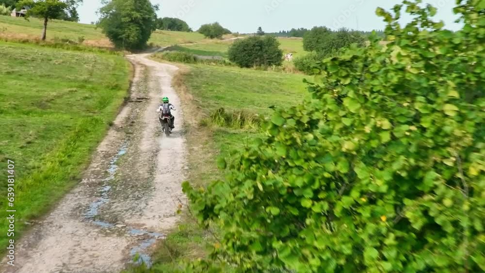 aerial shot of a motocross rider on a journey on a dirt and dusty country road driving fast and exploring beautiful nature while racing chased by the drone. aerial shot of a motocross rider on a journey on a dirt and dusty country road driving fast and exploring beautiful nature while racing chased by the drone.