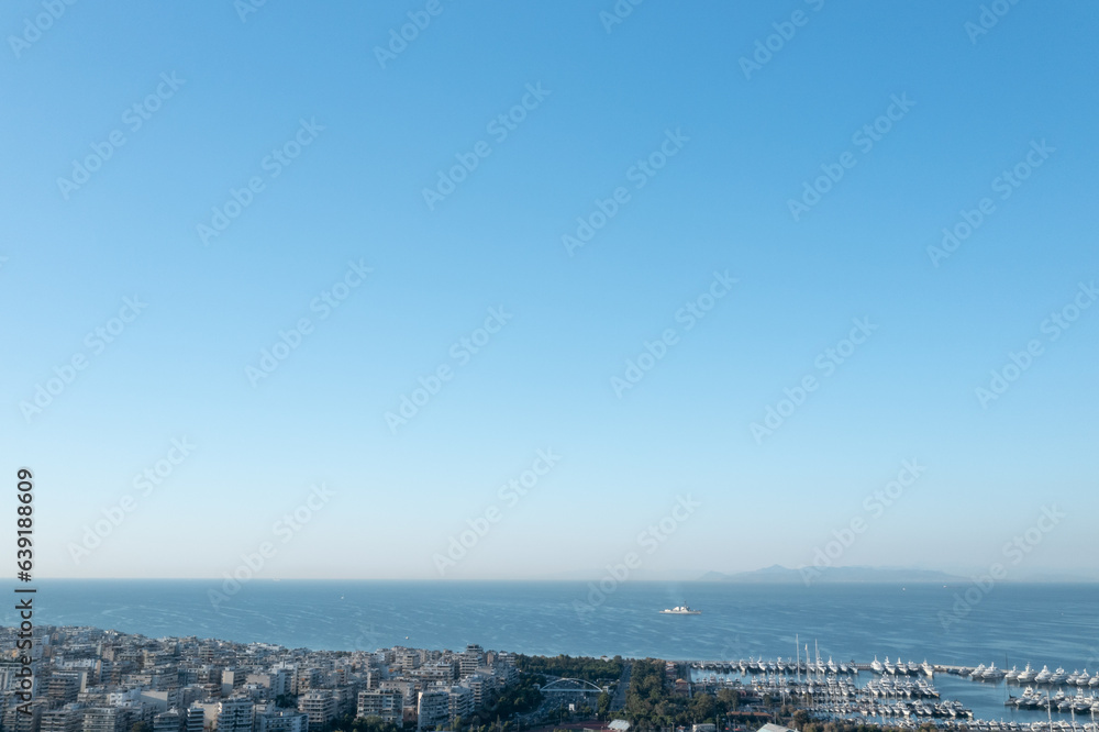 Athens' Seaside Vista: Urban Houses and Lone Ship on Calm Waters Athens' Seaside Vista: Urban Houses and Lone Ship on Calm Waters