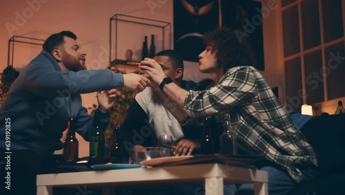 Drunk multiracial male friends eating pizza during night home party, alcoholism photo