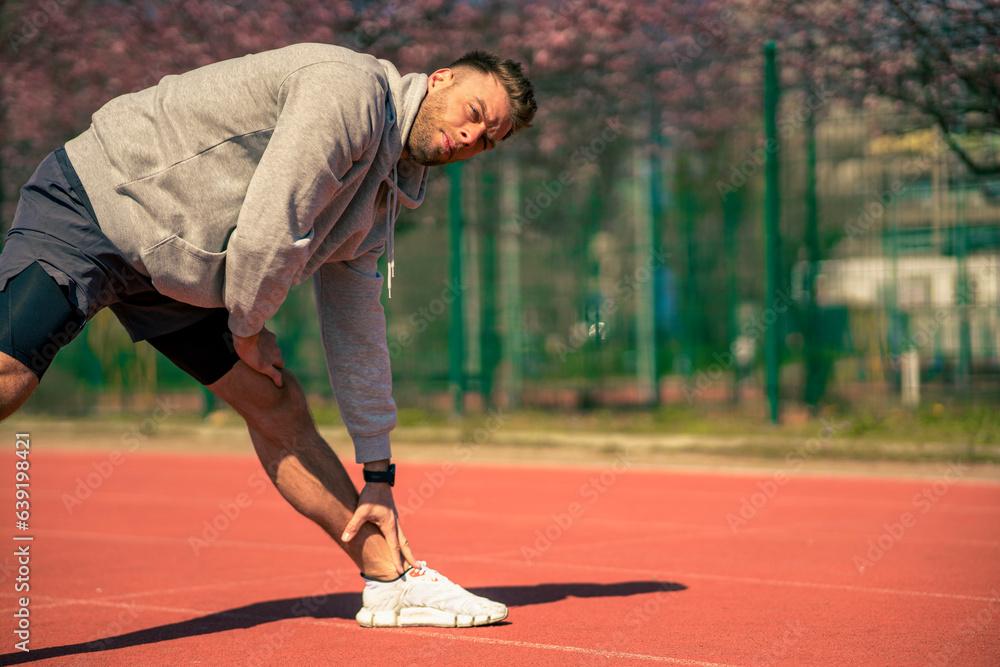 A muscular athlete stretches before a sports training session at a sports stadium