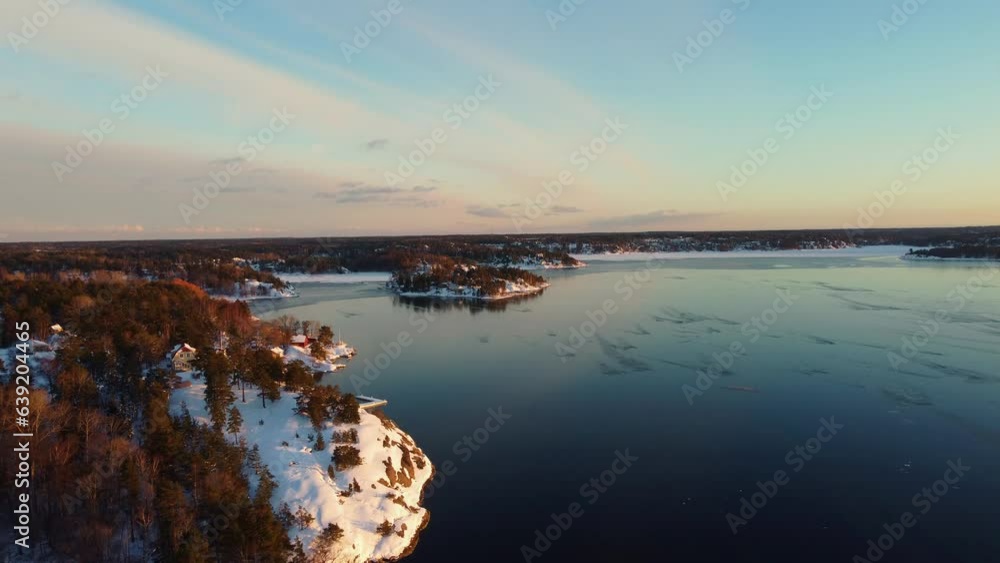 Beautiful winter sunset over a frozen landscape in Sweden. Residential houses and forest.