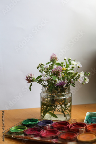 selective focus still life with wild flowers in a jar and water colors