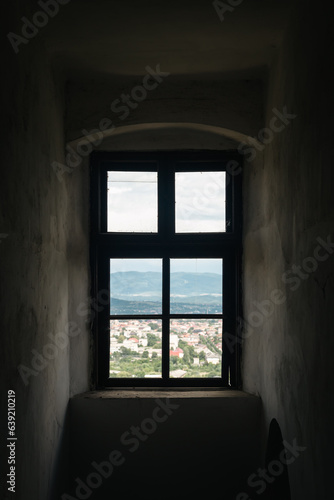 Old vintage castle window with view of mountains town, Palanok Castle in Mukachevo town, Ukraine.