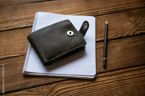 the wallet lies on a notepad with a hand on a wooden table top view