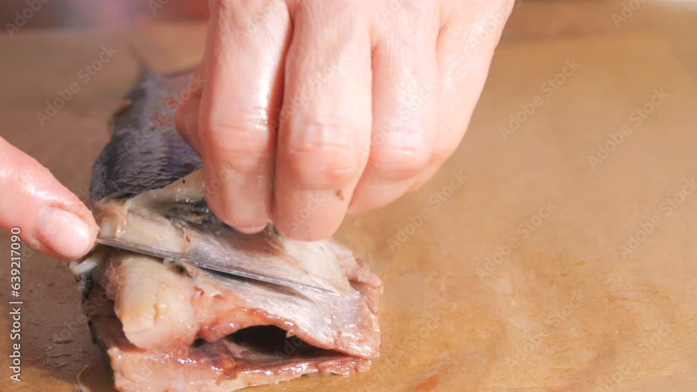 Female hands cuts herring and removes the skin in the home kitchen slow motion Female hands cuts herring and removes the skin in the home kitchen slow motion