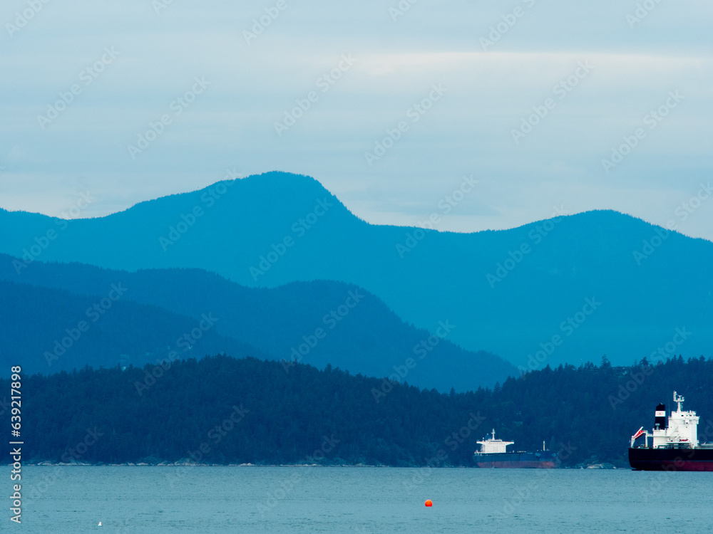 Blue background with mountains, sky and the ocean wit a ship