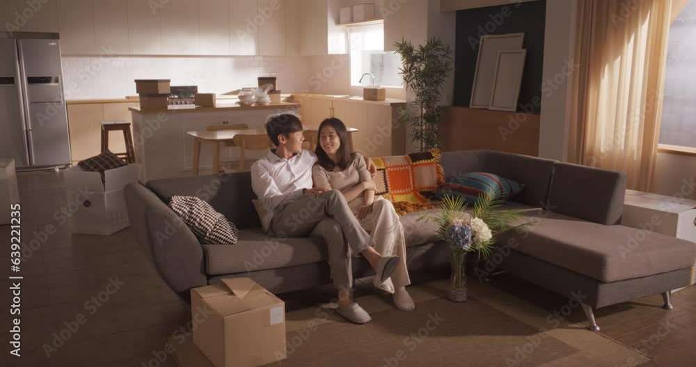 Family Moving in: Happy and Excited Young Korean Couple Sitting in Their Newly Purchased Apartment. Beautiful Family of Two Happily Embracing, Discussing How to Decorate Their New Home Family Moving in: Happy and Excited Young Korean Couple Sitting in Their Newly Purchased Apartment. Beautiful Family of Two Happily Embracing, Discussing How to Decorate Their New Home