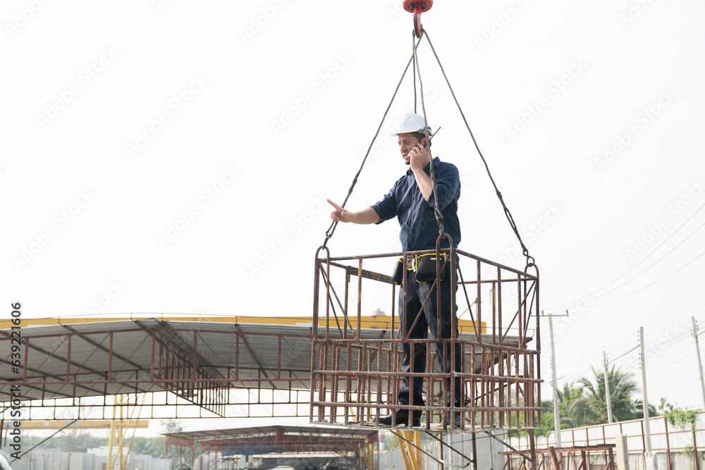 Foreman construction builder worker wearing safety uniform, helmet working on lift basket at construction site