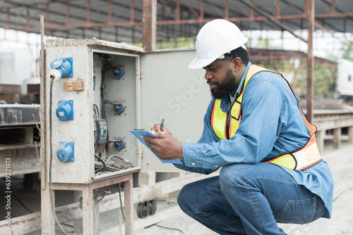 Male electrician engineer maintenance electric system at construction site work. African American male electrician engineer checking electric system at precast concrete wall construction site