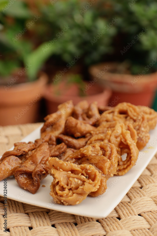 Moroccan chebakias on a white plate in a patio with plants Moroccan chebakias on a white plate in a patio with plants