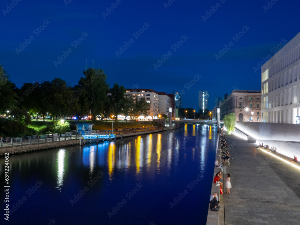 View of Berlin city river at dusk. Light trails along the river from evening lanterns.