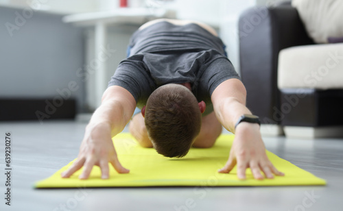 Young man is doing exercises to stretch his back muscles. Relief of problems and pain in the spine concept photo