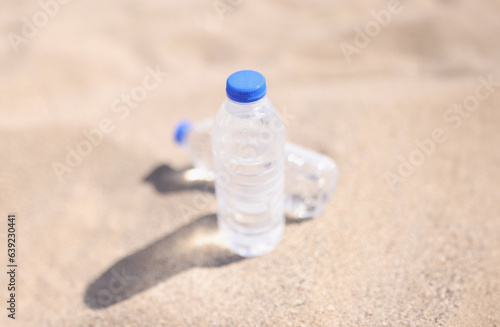 Plastic water bottles standing on hot sand closeup. High quality mineral water concept