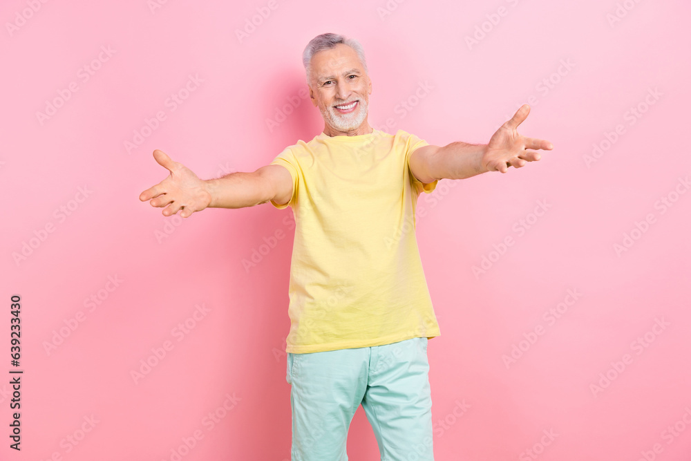 Photo of friendly cheerful senior man with white beard dressed yellow t-shirt stretching hands to you isolated on pink color background Photo of friendly cheerful senior man with white beard dressed yellow t-shirt stretching hands to you isolated on pink color background