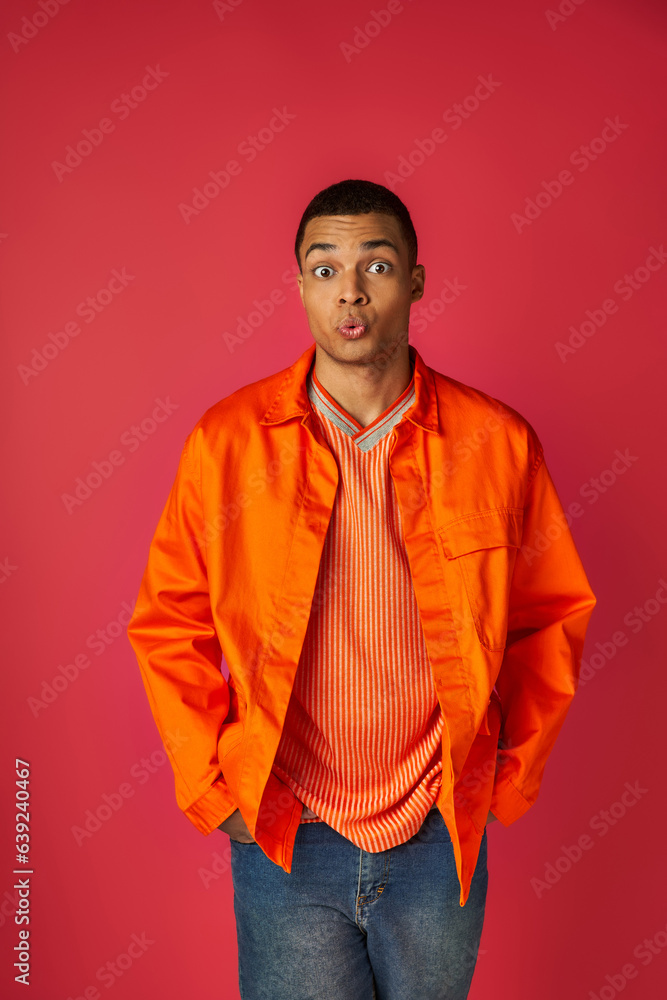 discouraged african american man pouting lips and looking at camera on red, orange shirt, stylish discouraged african american man pouting lips and looking at camera on red, orange shirt, stylish