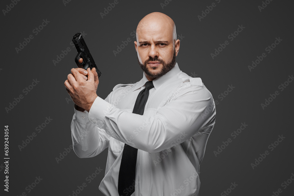 Strong bearded individual in crisp white attire readies his firearm, suggesting roles of security or detective