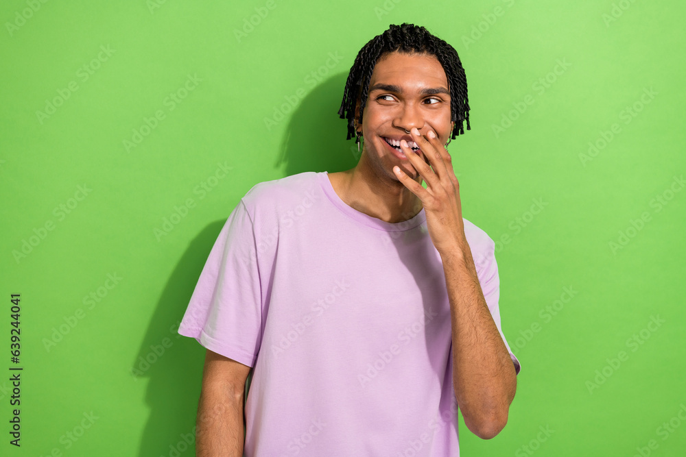 Portrait of cheerful excited man hand cover mouth look empty space laughing isolated on green color background Portrait of cheerful excited man hand cover mouth look empty space laughing isolated on green color background