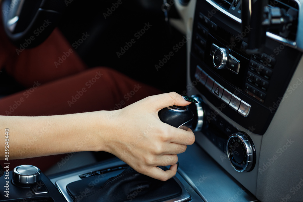 Young woman driver hand holds close up gear shift knob car