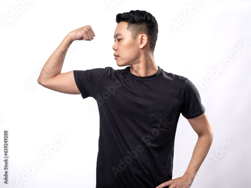 A portrait of an Asian man wearing a black shirt, stretching and showcasing his arm muscles. Isolated with a white background.