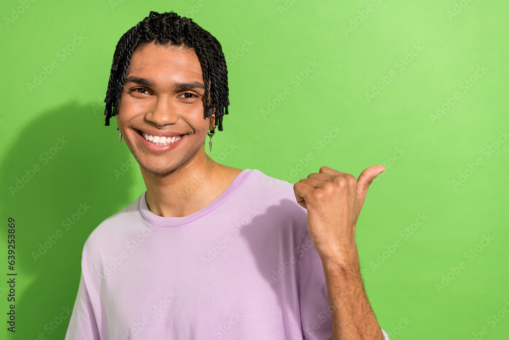Photo of attractive funky man toothy smile indicate finger empty space offer ad isolated on green color background Photo of attractive funky man toothy smile indicate finger empty space offer ad isolated on green color background