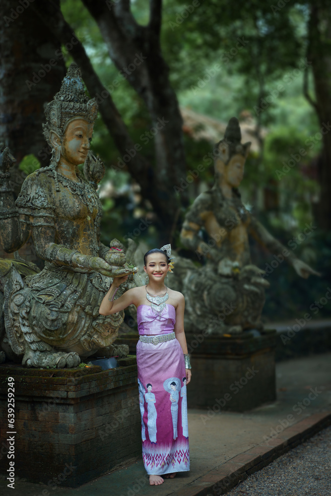 Pretty girl tourist teenagers wearing beautiful traditional Thai dresses travel to the ancient Wat Pha Lat Temple a famous place and attraction of Chiang Mai, Thailand.