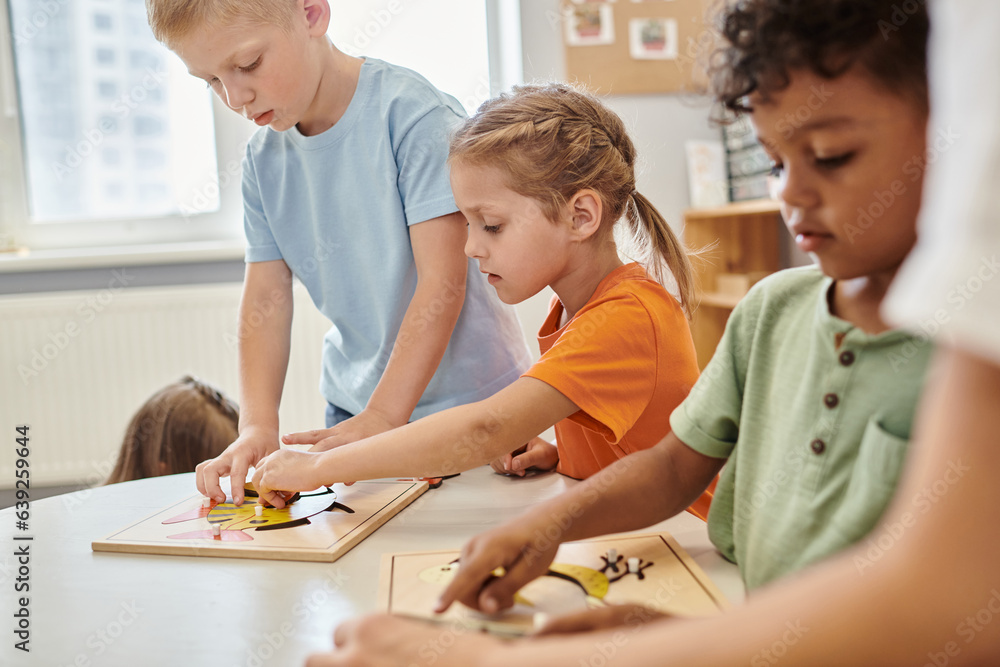 interracial children playing with didactic materials on table in ...