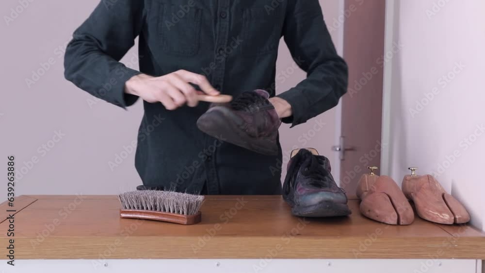 A craftsman cleans the sneakers of dirt with a small stiff shoe brush A craftsman cleans the sneakers of dirt with a small stiff shoe brush
