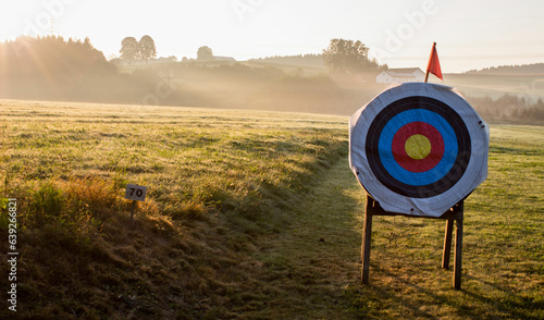 Archery target at an archery course with golden sunrise and fog in the background photo