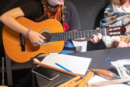 A woman in folk clothes playing guitar