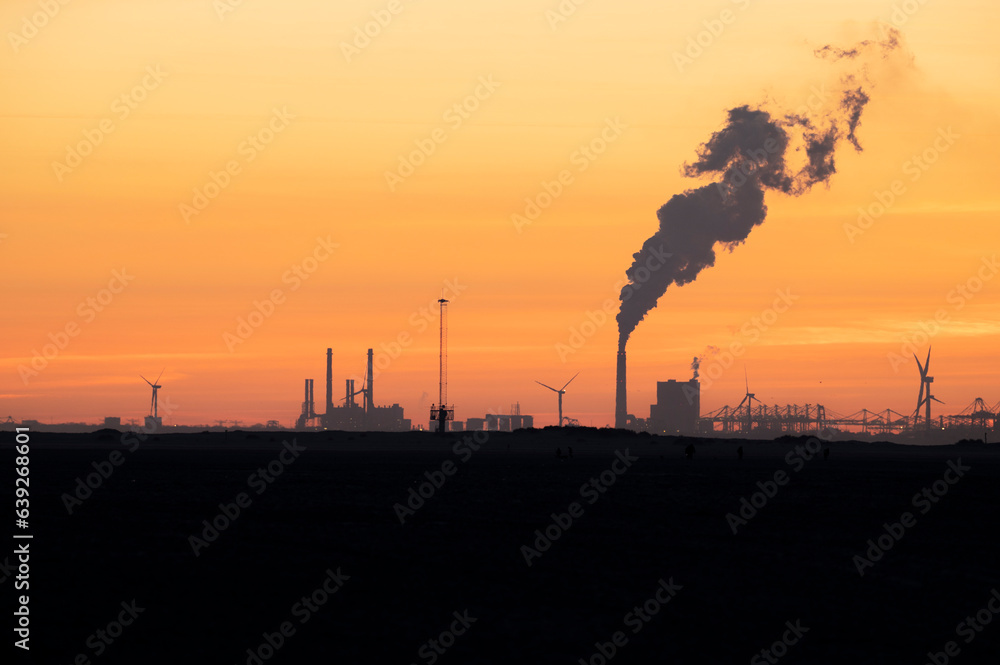 Power station with sunset as a silhouette. With steam in the sky. Nature with industry.