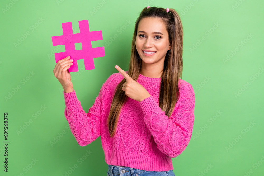 Portrait of good mood positive girl with straight hairstyle wear knit pullover indicating at hashtag isolated on green color background Portrait of good mood positive girl with straight hairstyle wear knit pullover indicating at hashtag isolated on green color background