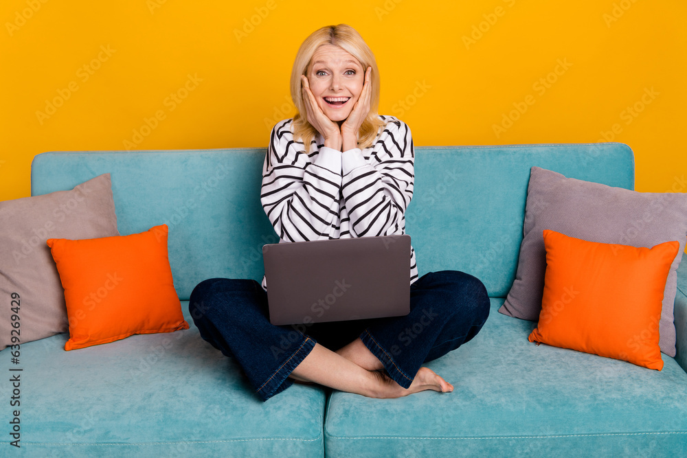 Photo of shocked surprised retired lady sitting couch using netbook for browsing discounts isolated bright color background Photo of shocked surprised retired lady sitting couch using netbook for browsing discounts isolated bright color background