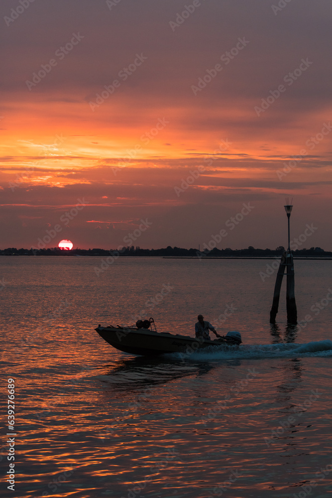 Un motoscafo naviga veloce sull'acqua della laguna di Venezia alle prime luci dell'alba
