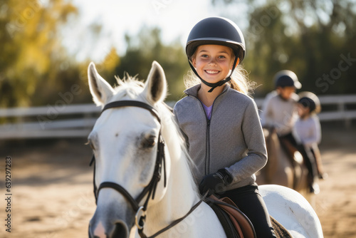 Foto Happy girl kid at equitation lesson looking at camera while riding a horse, wear
