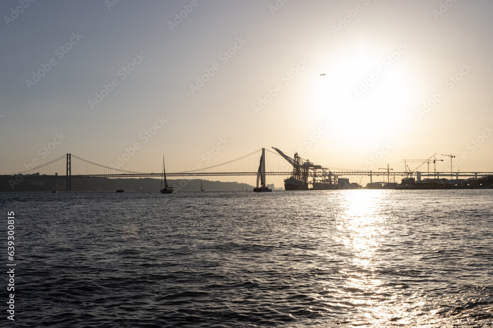 Bridge, boats and industrial cranes - sunset over the river Bridge, boats and industrial cranes - sunset over the river