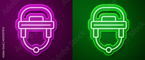 Canvas Print Glowing neon line Hockey helmet icon isolated on purple and green background