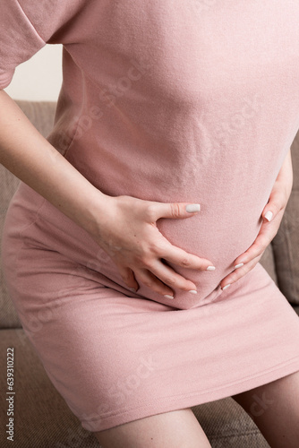 Wallpaper Mural Pregnant Lady Having Massaging Lower belly Sitting On Sofa Indoor. Pregnancy Problems Concept. Maternity healthcare Torontodigital.ca