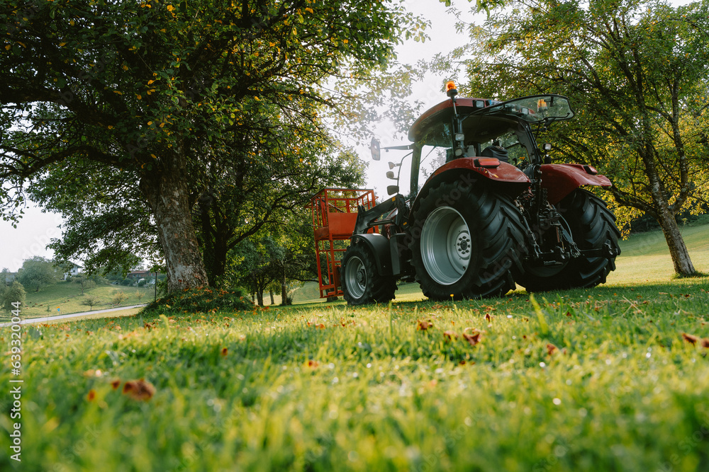 Obraz premium red machine tractor on bright green grass 
