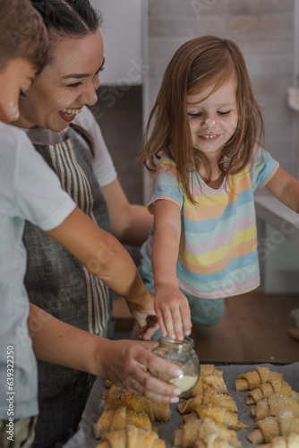 One woman with one toddler girl and one  preschooler boy in the kitchen making croissant and preparing for baking