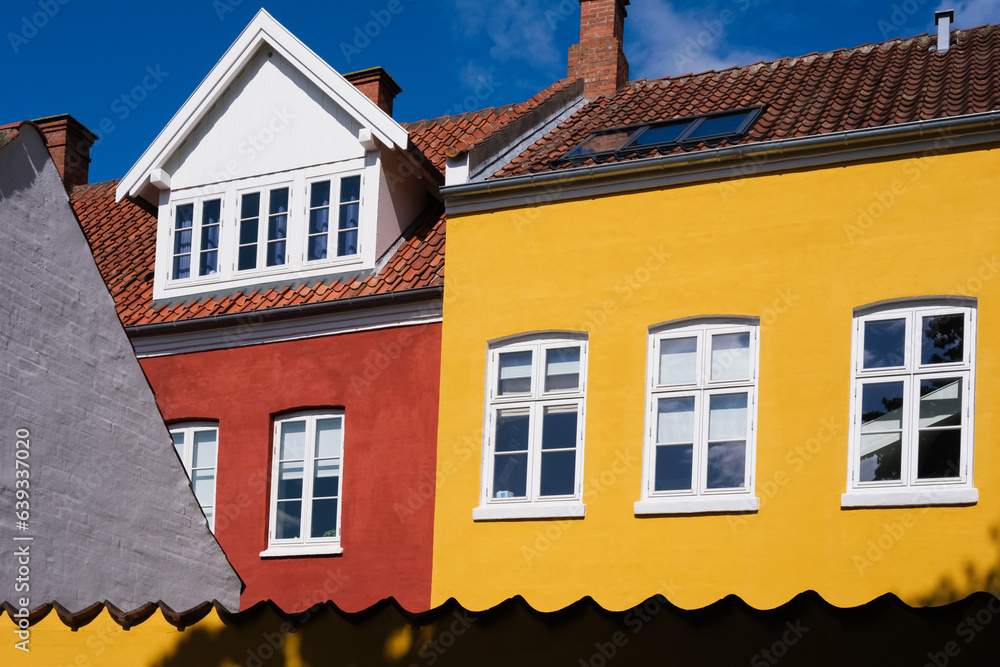 Traditional houses painted in striking color, red yellow against the blue sky and intense sun.